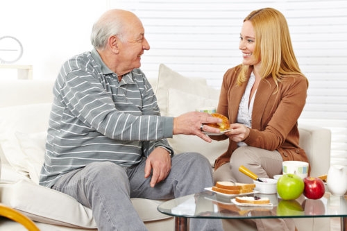 old man with his caregiver eating a breakfast together